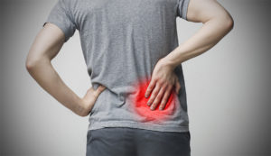 Young man holding his painful inflamed lower back