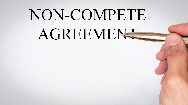 Hand holding pen hovering above a non-compete agreement